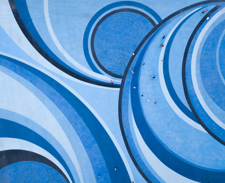 Aerial Drone View Of People Walking Over A Circular Swirl Patterned Blue Floor