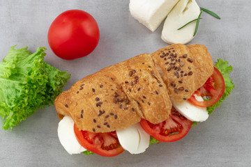 Croissant sandwich with lettuce mozzarella and tomato. Healthy snack. Top view
