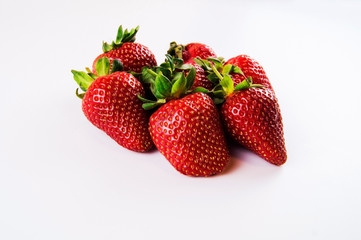 Big red strawberry in a pile on a white background