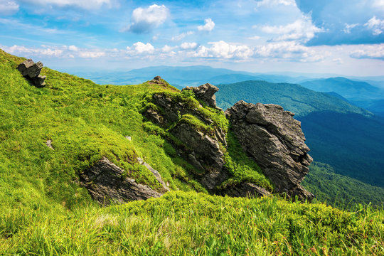 rocky cliff on a grassy slope. beautiful scenery in mountains. huge ridge in the distance. wonderful summer weather