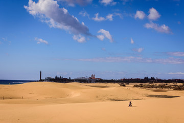 People walking on dunes against Maspalomas lighthouse, Gran Canaria, Spain