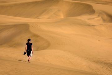 Fototapeta na wymiar woman walking on dunes in maspalomas, spain