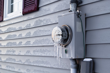 Frozen electrical utility meter on house  exterior siding.