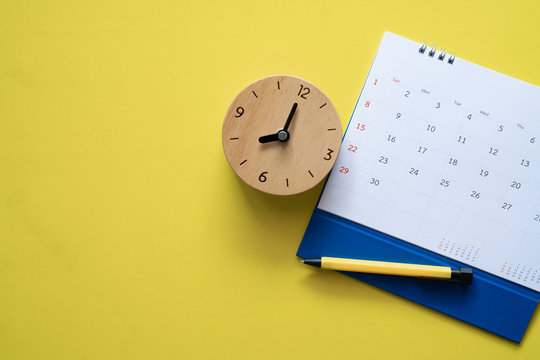close up of calendar, clock and pen on the yellow table, planning for business meeting or travel planning concept