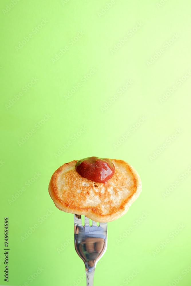 Poster One pancake with strawberry jam on a green background. Food on fork