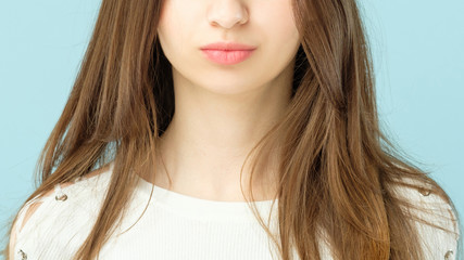 Female plumpy lips. Beauty concept. Girl with long brown hair and clean fresh skin looking toward camera.