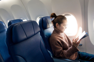 Beautiful Asian woman is working with tablet computer  in airplane