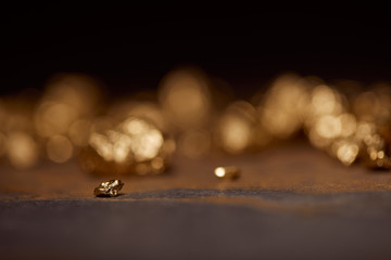 selective focus of small golden stone on grey and brown marble surface with blurred background
