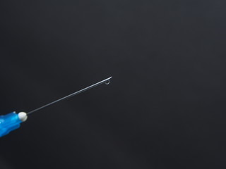 Fototapeta premium A drop of medicine on the end of a medical syringe needle.