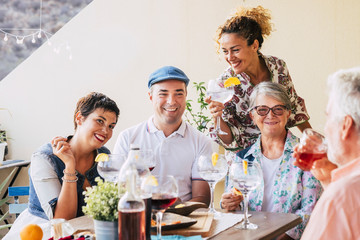 Family and friends at lunch all together at home in the terrace - eating and drinking food and...