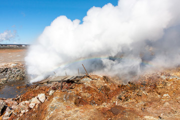 A boiling sulphur spring produces dense vapor forming a rainbow, Gunnuhver, Iceland