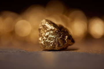 selective focus of golden stone on grey marble and blurred sparkling background