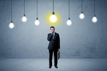 Obraz premium Handsome businessman in an empty space with bulbs above and uninspired face 