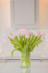 A fresh and clean home office with soft pink tulip flowers in a kitchen for Women's Day celebration. Airy Scandinavian/Nordic interior style on a media office in Finland.