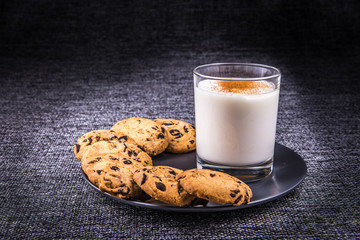 A glass of milk with cinnamon and chocolate chip cookies.