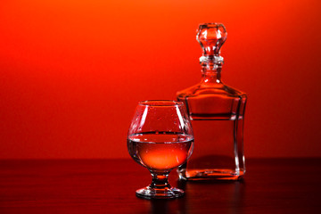 glass and carafe with alcohol on a red background
