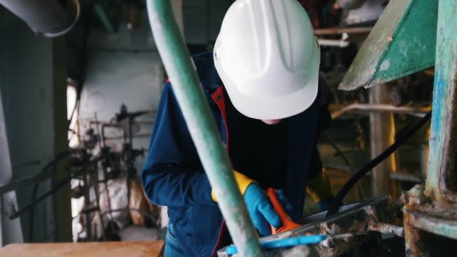 A man engineer in manufacturing plant cheking the equipment with a flashlight