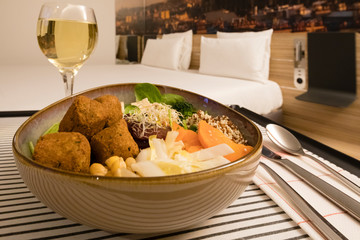 Hotel Room service: vegan meal and white wine with the bed in the backgroud