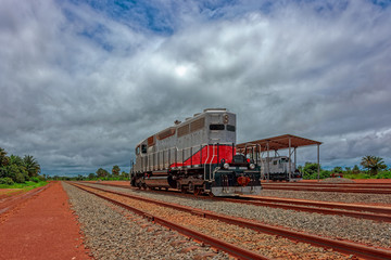 Obraz premium Freight diesel locomotive parked on train tracks at the end of the railway line built for bauxite ore transshipment. Guinea, Africa.