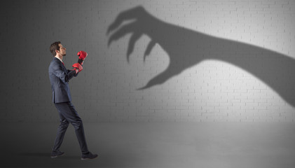 Fototapeta premium Tiny businessman fighting with scary hand shadow 
