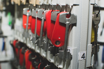 Many keys with red plastic  tags hanging on metal hooks 