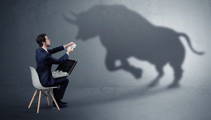 Humble businessman staying and offering stuffs to a huge angry bull shadow
