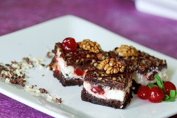 Milk mousse cake decorated with cherry and walnuts