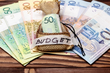 wooden background. On it the Belarusian money is laid out. In the center in a bag of 50 rubles. retiree's hand holds. inscription budget