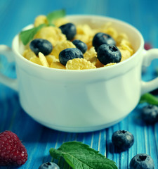 Healthy eating, food  and diet concept - Cornflakes with berries raspberries and blueberries  on blue wooden background. Top view.