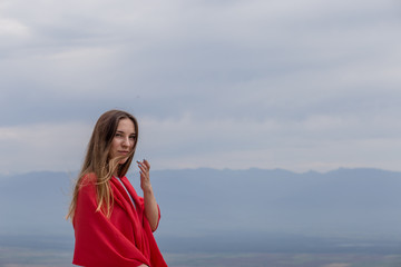 young beautiful happy girl with a red scarf on her shoulders travels around Georgia