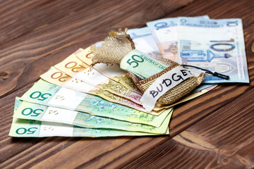 wooden background. On it the Belarusian money is laid out. In the center in a bag of 50 rubles. retiree's hand holds. inscription budget