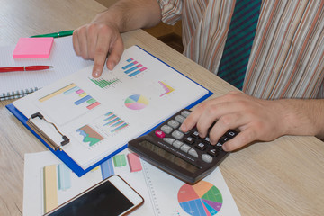 man working on office desk with Calculator, a pen and papers. Businesses concept