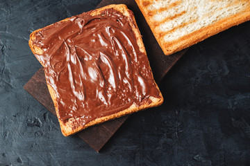 Toast with chocolate hazelnut cream on dark background, top view