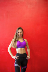 Fototapeta na wymiar Fit woman is standing near a wall in a gym