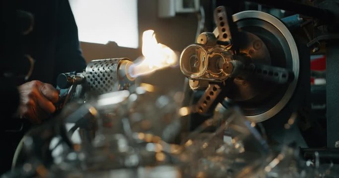 Slow motion of experienced glass blower working with flame on a handmade art piece of glass from precious crystal in a workshop.Shot in 8K.Concept of handmade,quality,artisan, made in Italy,glass blow