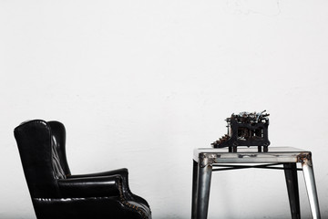 Old vintage typewriter on table with leather chair on white background