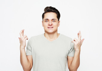  Portrait of charming caucasian man raising hands with crossed fingers and smiling