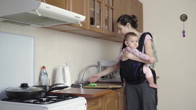 Busy Mother With Baby In Sling At Home washing dirty dishes 4k