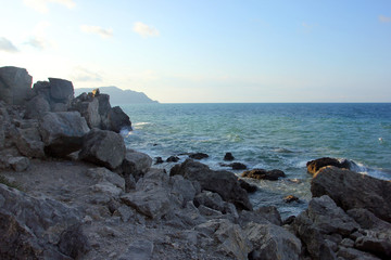Fototapeta na wymiar beautiful picturesque wild Black sea coast with big dark boulders and rocks in blue sea water