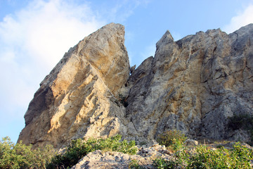 Fototapeta na wymiar beautiful big high relief rocky stone cliff of sandy color on blue sky background in crimea