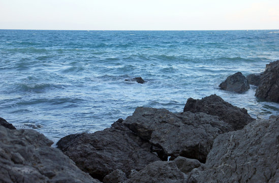 beautiful picturesque wild Black sea coast with big dark boulders and rocks in blue sea water