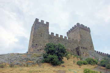Fototapeta na wymiar beautiful old ancient mountain castle - Genoese fortress with stone walls with battlements on top of the stone mountain in Crimea. The medieval citadel