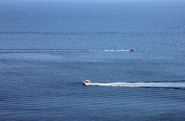 best blue sea in full screen and small ripples on the water and two motor boats cross the water surface