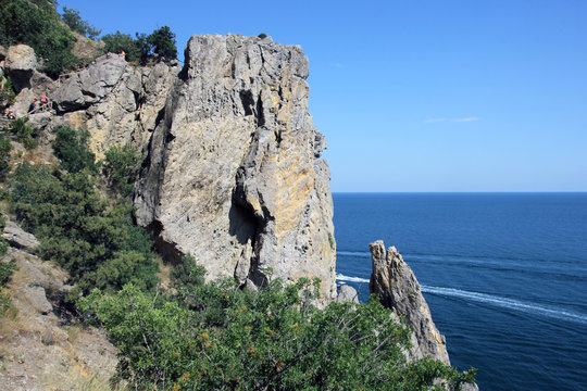 beautiful panoramic view of a large steep stone cliff on the deep blue sea and green trees in Crimea