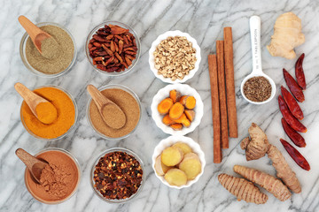 Fat busting spices for weight loss with fresh and dried turmeric,  ginger, cumin, chilli, cinnamon and gymnema sylvestre used to suppress appetite. Top view on marble background.