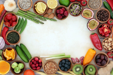 Healthy super food background border on parchment with fresh fish, fruit, vegetables, seeds, grains, nuts, herbs & spices. Very high in antioxidants, anthocyanins, vitamins & dietary fibre. Top view.