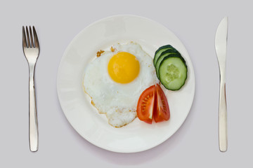 tasty and healthy breakfast of fried eggs, slices of cucumber and tomato slices