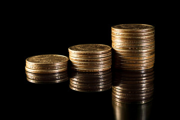 Stacks of gold coins on black reflective background. Business grows concept.