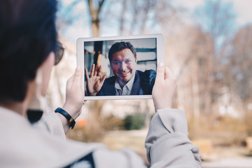 Young woman using a tablet by having a video call chat with her businessman boyfriend who is away...