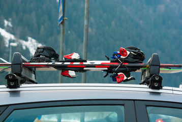 Luggage rack with colored skis and snowboards on a car
